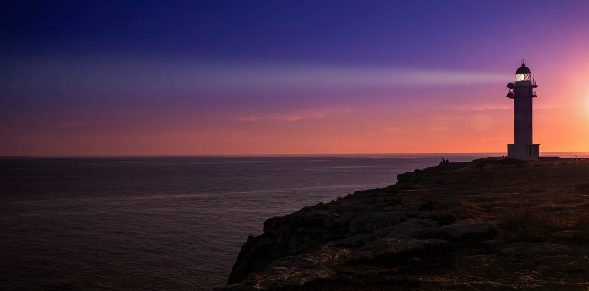 Formentera lighthouse shines beacon during sunset