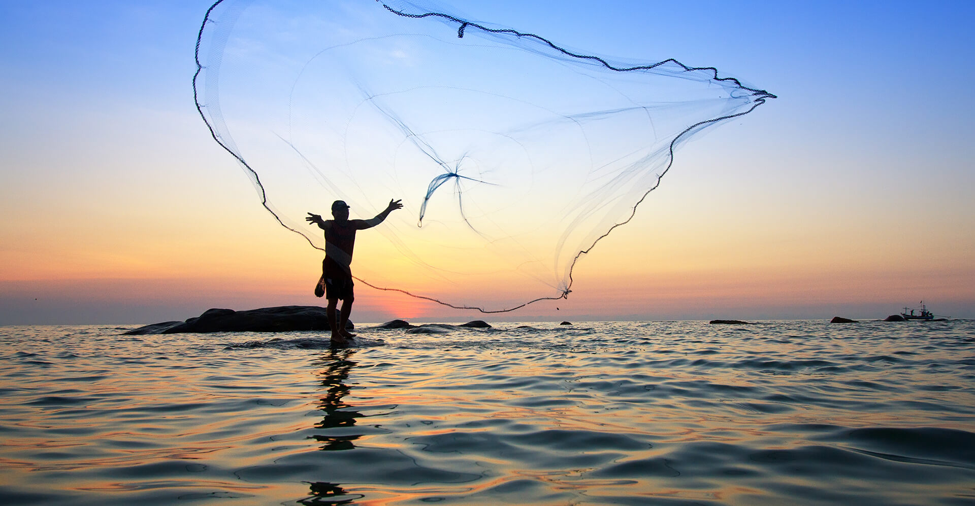 Man throws out fishing net during sunrise